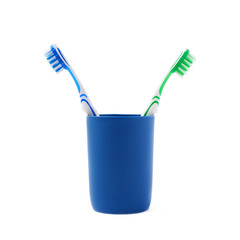 Pair of toothbrushes in blue plastic cup isolated over white background