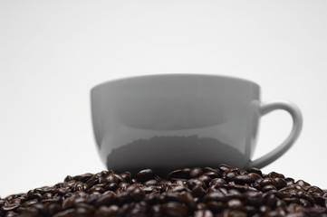 Closeup of cup on heap of beans isolated over gray background