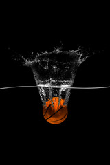 Basketball falls into the water on black background