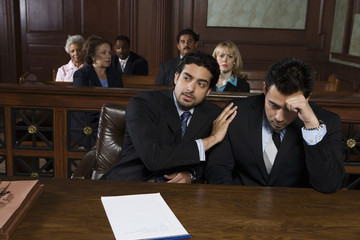 Advocate consoling upset client in the courtroom