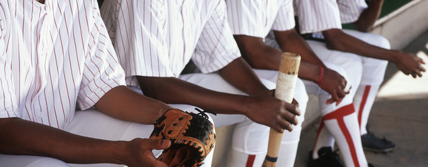 Midsection of baseball players sitting together in dugout