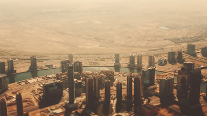 True tilt shift shooting from top of Dubai skyscrapers, residential buildings, river and highways on sunny summer day with haze
