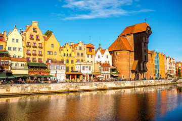 Obraz premium Morning view on the riverside of Motlawa river with beautiful buildings and famous historic gate of the old town in Gdansk, Poland