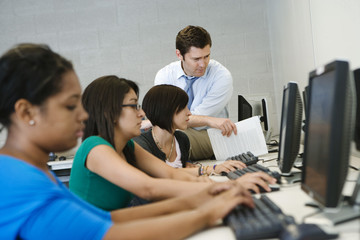 High school teacher helping students in computer lab
