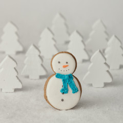 Gingerbread snowman Christmas cookie in front of snowy pine tree