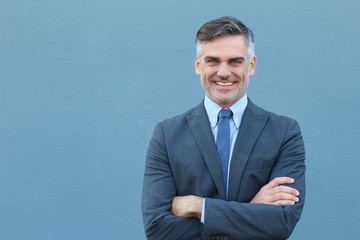 Mature handsome Caucasian businessman smiling with arms crossed 