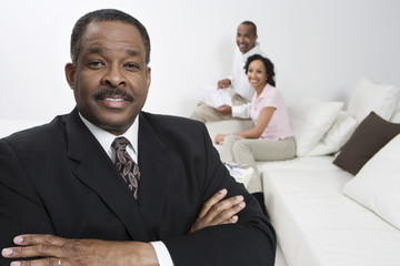 Portrait of confident financial advisor with happy couple in background