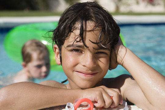 Portrait of a happy little boy resting at edge of swimming pool
