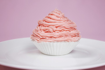 Closeup of a cupcake on plate isolated over pink background