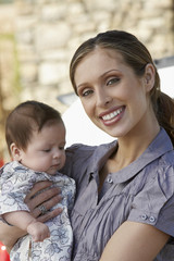 Portrait of a happy young mother carrying baby