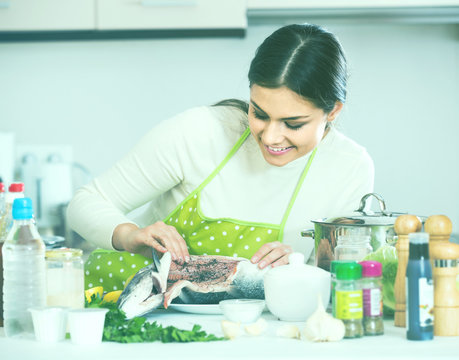 girl eviscerating salmon fish in domestic kitchen
