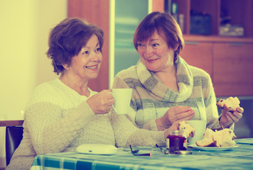 Fototapeta premium Mature women watching movie and drinking tea indoor