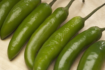 Detail of green chili peppers in a row on chopping board