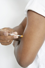 Closeup midsection of an African American man injecting insulin using syringe