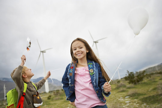 Little boy and girl playing with balloons at wind farm