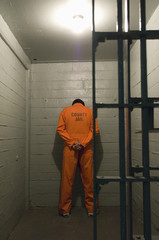 Prisoner standing against the wall in prison cell