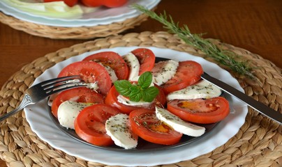 Fresh healthy vegetable salad with mozzarella, tomato and basil on a plate