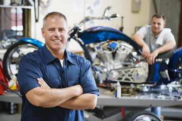 Portrait of a confident mechanic with coworker at motorcycle shop