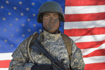 Portrait of US army soldier with gun standing in front of the American flag