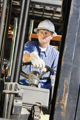 Confident male industrial worker driving a forklift at workplace