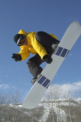 Low angle view of male snowboarder in winter clothes jumping while showing victory sign against sky