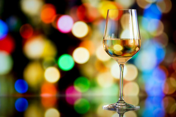 glass of white wine against a glowing bokeh - copy space, select