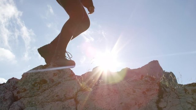 CLOSE UP: Unrecognizable female in leather walking boots climbing mountains