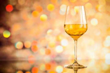 glass of white wine against a glowing bokeh - copy space, select