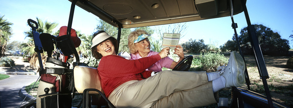 Two women laughing in golf cart with scorecard