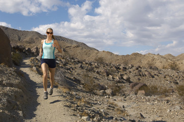 Fototapeta premium Full length of a Caucasian woman jogging in mountains