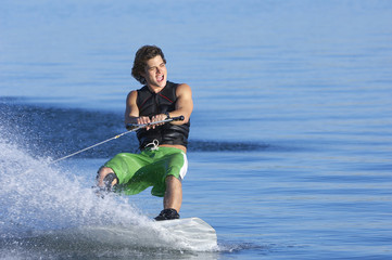 Young Caucasian man wakeboarding on lake