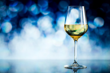 glass of white wine against a glowing bokeh - copy space, select