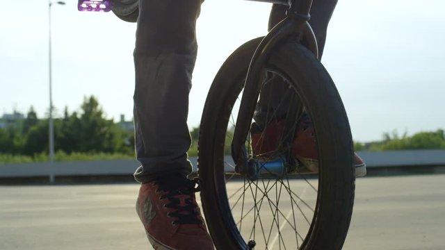 SLOW MOTION CLOSE UP: Extreme bmx biker riding manual trick at sunset