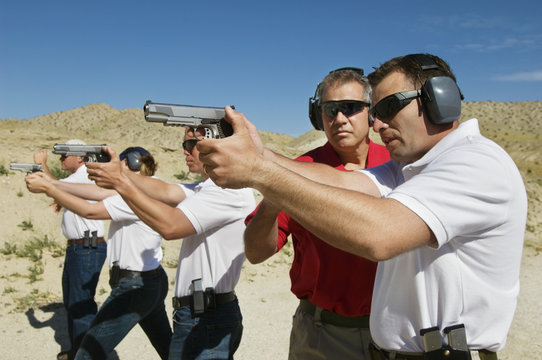 Instructor Assisting Officers With Hand Guns At Firing Range During Weapons Training