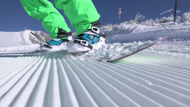 Slow motion close up extreme snowboarder riding on groomed snow in ski resort
