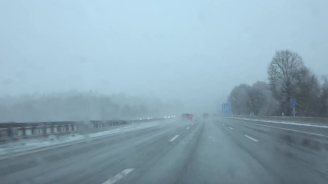 FPV: Cars driving fast in snowstorm on slippery frosty road with low visibility