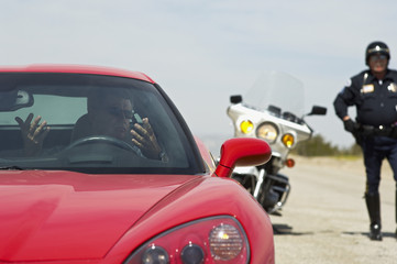 Driver of sports car gesturing after being caught by the traffic cop