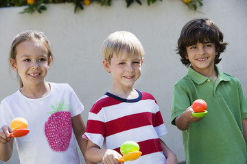 Portrait of three happy kids holding eggs in spoons for egg race