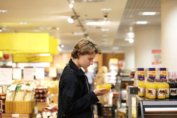 Man shopping in supermarket reading product information