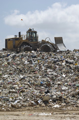 An Excavator moving trash at dumping ground