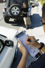 Fototapeta premium Closeup of police officer writing ticket with man in the background