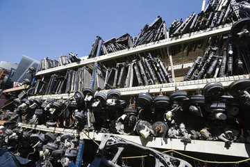 Old waste vehicle parts on rack at an automotive scrap yard