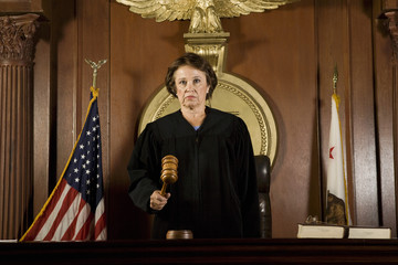 Portrait of a senior female judge forming a judgment in courtroom