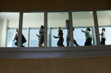 Low angle view of multi ethnic scared business people running down hallway