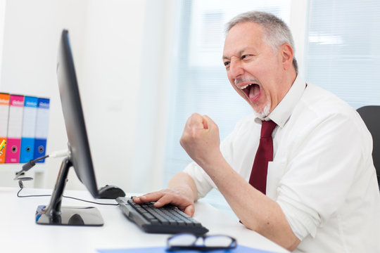 Very happy businessman looking at his computer monitor