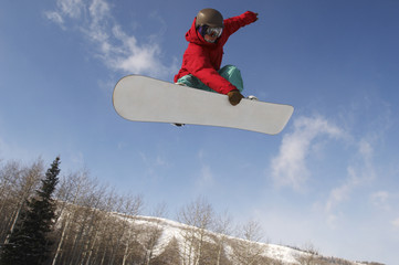 Low angle view of young male snowboarder jumping against sky