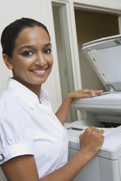 Portrait of a happy business woman using fax machine in office