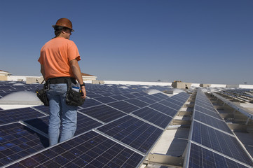 Electrical engineer among solar panels at solar power plant
