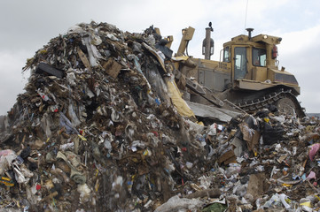 Excavator moving garbage at dumping ground