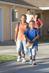 Fototapeta premium Portrait of happy preadolescent boys walking with parents in the background